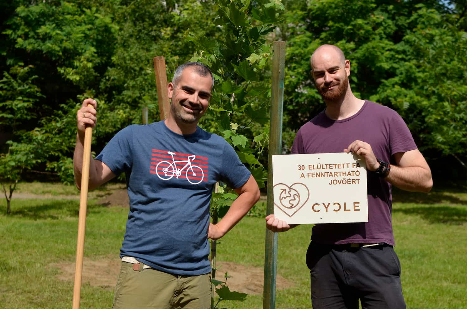 CYCLE team members uphold a board saying that 30 new trees were planted for the sustainable future